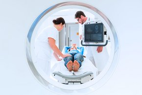 (Foto: Kzenon) Ein Arzt und eine Pflegekraft betreuen eine Patientin bei der Computertomographie.