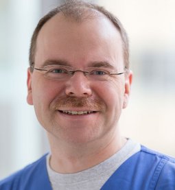 Söllner (Uwe Moosburger) Herr Söllner trägt blaue Arbeitskleidung, hat einen Schnurrbart und eine Brille