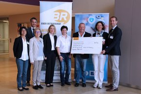Spende Continental (Krankenhaus Barmherzige Brüder Regensburg) Zu sehen sind 8 Personen, die sich über die Übergabe des Spendenschecks freuen.