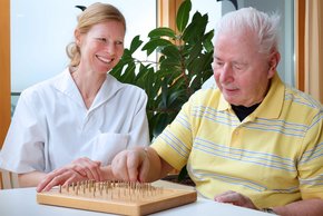Parkinsonpatiententag 2018 (Foto: Clemens Mayer) Ergotherapeutin Iris Stahl übt mit ihrem Patienten bei der Parkinsonkomplex-Behandlung am Steckbrett die Feinmotorik.