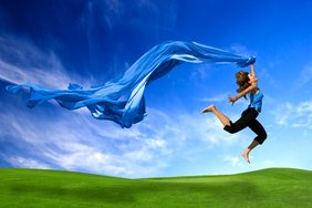 Selbsthilfe Glück (Fotolia) Man sieht eine Frau, die glücklich und frei über den Rasen schwebt.