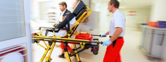 zwei Sanitäter bringen gerade einen Patienten auf der Liege ins Notfallzentrum.