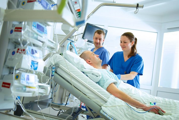 Zwei Pflegekräfte kümmern sich auf der Intensivstation um einen Patienten.