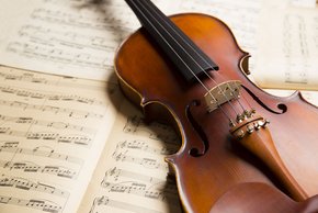 Violine (Fotolia) man sieht eine Violine, die auf einem Notenblatt liegt.