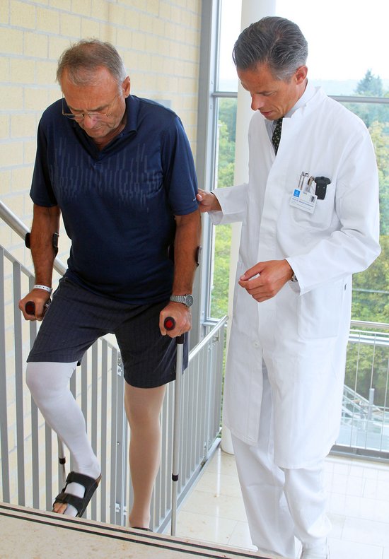Prof. Bernd Füchtmeier unterstützt einen seiner Patienten bei der Physiotherapie.