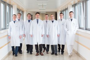 Team der Urologie (Paul Mazurek) Man sieht das große männliche Team der Urologie, die zusammen den Flur im Krankenhaus mit dem Gesicht zu uns gewandt, vorangehen