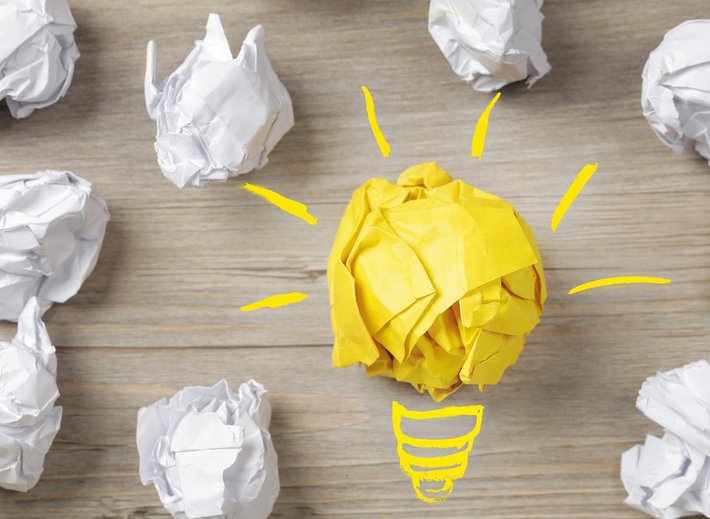 Eine Birne und Papierbälle stehen für "Idee, Konzept"